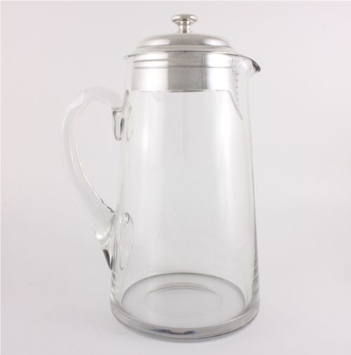 fig 2. A clear glass water jug with a silver-plated hinged lid, integrated strainer spout, and curved glass handle.