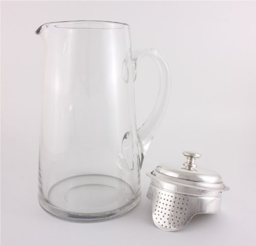 fig 3. A clear glass water jug with a silver-plated hinged lid, integrated strainer spout, and curved glass handle.