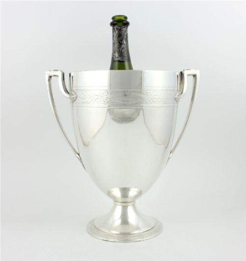 fig 3. An antique silver-plated urn-shaped champagne cooler featuring twin angular handles, a foliage engraved band, and a stepped pedestal foot.
