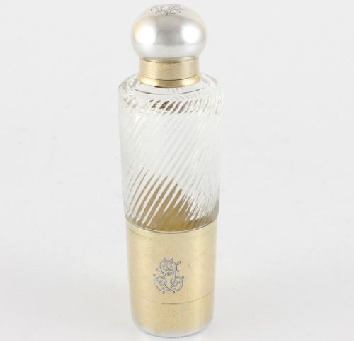 A cylindrical clear glass flask featuring spiral fluting, topped with a domed silver cap and a silver base bearing an engraved monogram.
