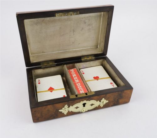 fig 1. A domed burr walnut box featuring polished brass strapwork depicting three playing cards on the lid and a brass keyhole escutcheon on the front.