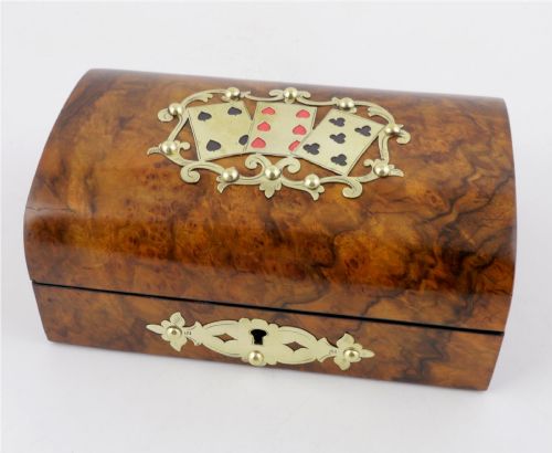 fig 2. A domed burr walnut box featuring polished brass strapwork depicting three playing cards on the lid and a brass keyhole escutcheon on the front.