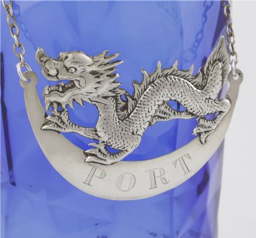 fig 1. An antique Chinese silver decanter label depicting a chased dragon above a crescent plaque engraved with PORT, attached to a chain.