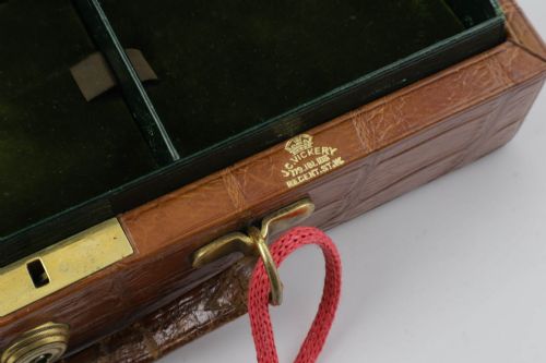 fig 5. An open brown crocodile leather jewellery case featuring a green velvet lined interior with multiple compartments and brass lock hardware.