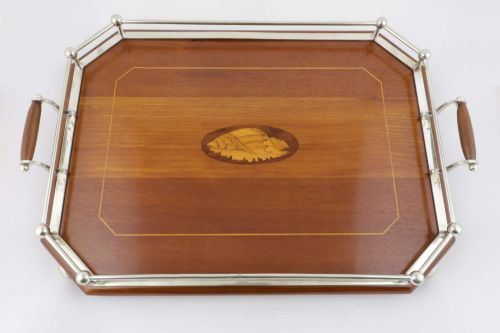 fig 2. An octagonal brown wooden serving tray featuring a shell marquetry inlay and a polished silver-plated gallery rail.