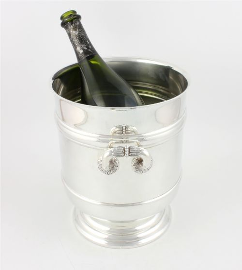fig 1. A polished silver-plated champagne cooler featuring side handles with leaf detailing and a stepped pedestal base.