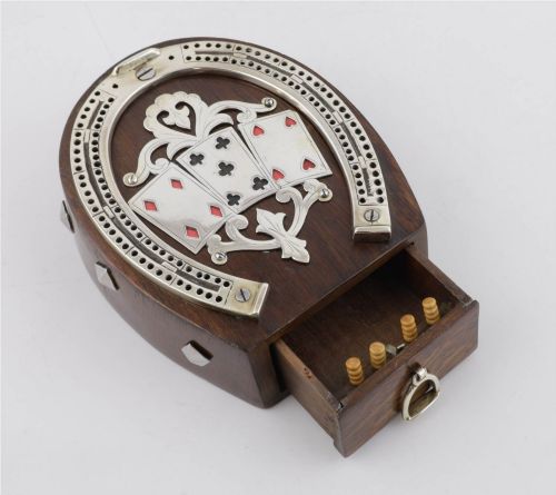 fig 1. An antique horseshoe-shaped dark oak games box featuring silver metal scrollwork, playing card motifs, and an integrated cribbage scoring track.
