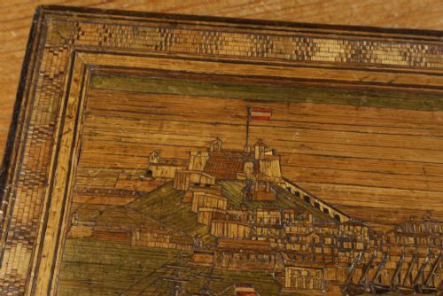 fig 4. A rectangular wooden box top featuring intricate straw marquetry depicting a harbour landscape with ships, fortresses, and geometric borders.