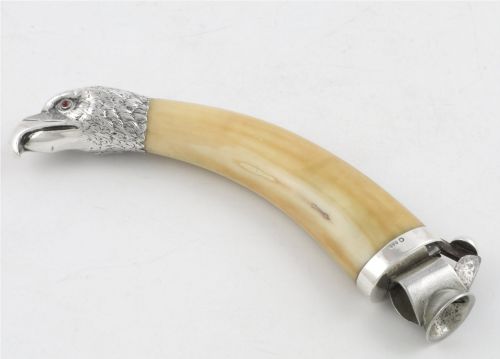 fig 2. An antique cigar cutter crafted from a curved cream-coloured boar tusk fitted with a cast silver eagle head terminal and a silver cutting mechanism at the opposing end.