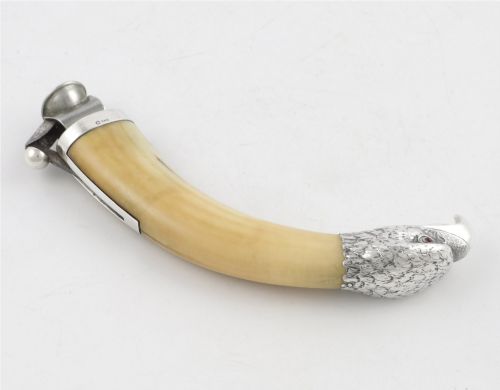 fig 3. An antique cigar cutter crafted from a curved cream-coloured boar tusk fitted with a cast silver eagle head terminal and a silver cutting mechanism at the opposing end.