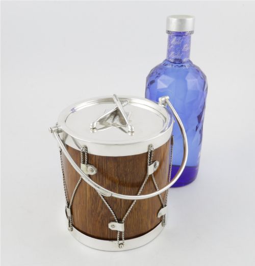 fig 1. A cylindrical English oak ice pail shaped like a military drum, featuring silver-plated trim, rope-work detailing, a swing handle, and a lid topped with crossed drumsticks.