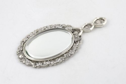 fig 2. An antique silver hand mirror featuring a dragon motif frame and an interconnected faux-bamboo handle.