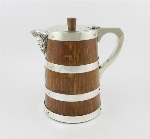 fig 1. A Victorian coopered oak wine pitcher featuring silver-plated bands, a detailed Bacchus spout, and a hinged lid with a wooden finial.
