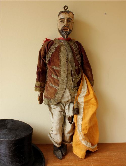 fig 2. An antique French folk art marionette puppet with a hand-carved bearded wooden head, articulated limbs, and a brown velvet jacket trimmed with braid.