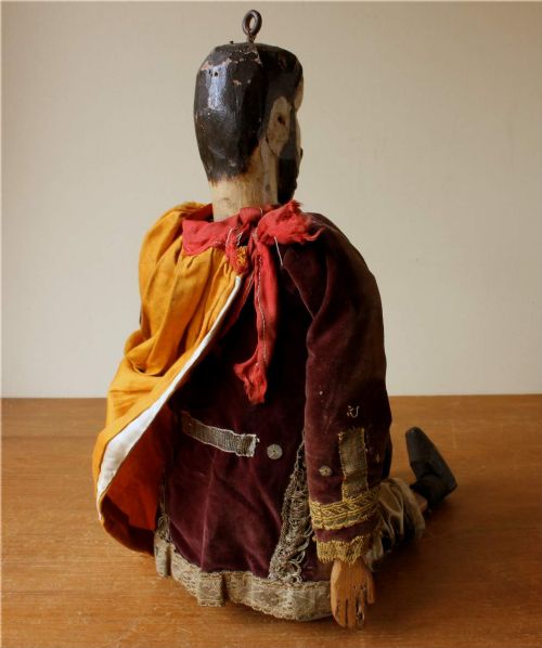 An antique French folk art marionette puppet with a hand-carved bearded wooden head, articulated limbs, and a brown velvet jacket trimmed with braid. View V