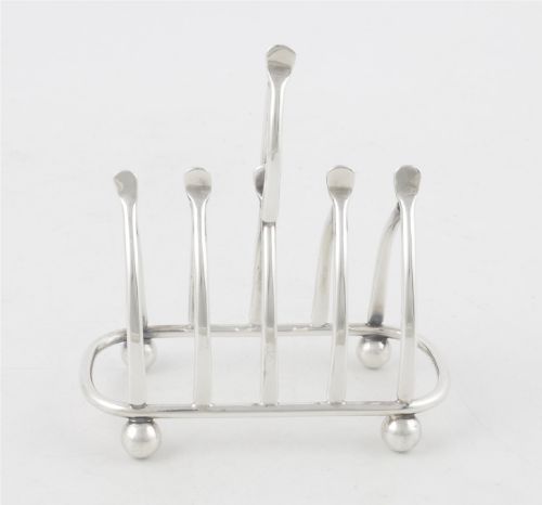 fig 1. An antique silver-plated wishbone toast rack featuring four divisions and spherical feet against a plain background.