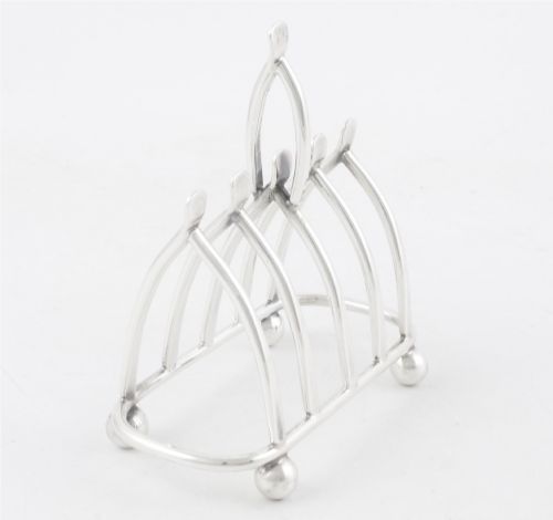 fig 2. An antique silver-plated wishbone toast rack featuring four divisions and spherical feet against a plain background.