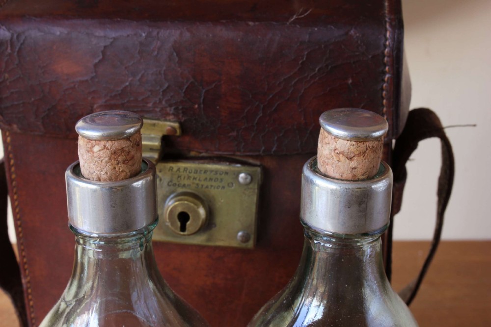 A Victorian brown leather carrying case with a brass lock mechanism, leather shoulder strap, key, and two clear glass spirit bottles. View XII