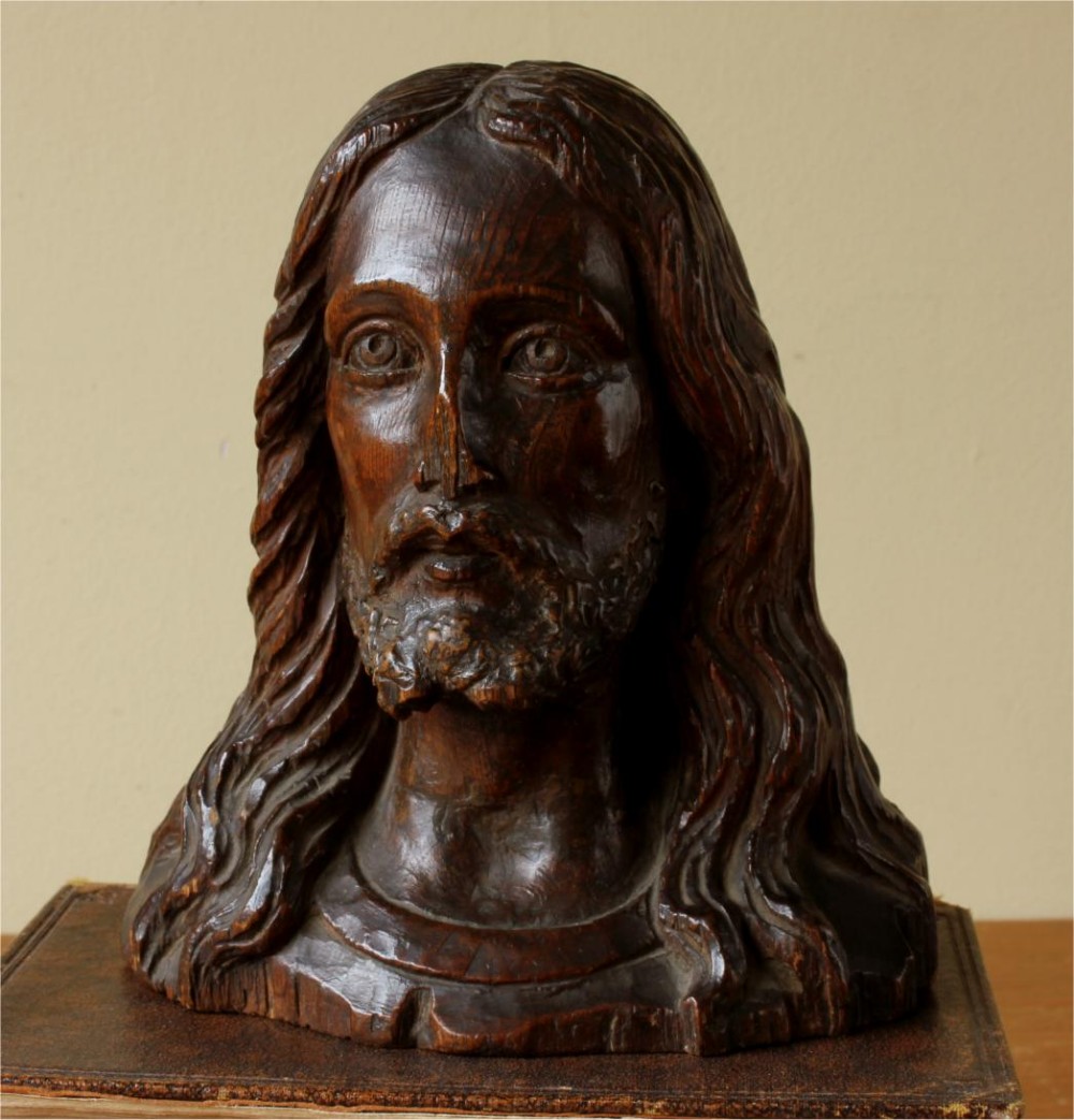 A 19th-century hand-carved dark wood bust depicting Jesus Christ with long wavy hair, a beard, and detailed facial features.