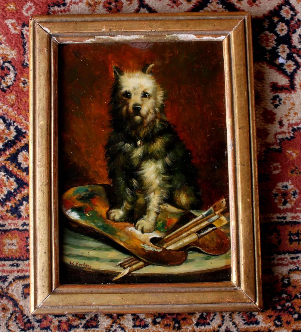 An antique framed oil painting depicting a small terrier dog sitting beside an artists palette and paintbrushes against a dark warm background.