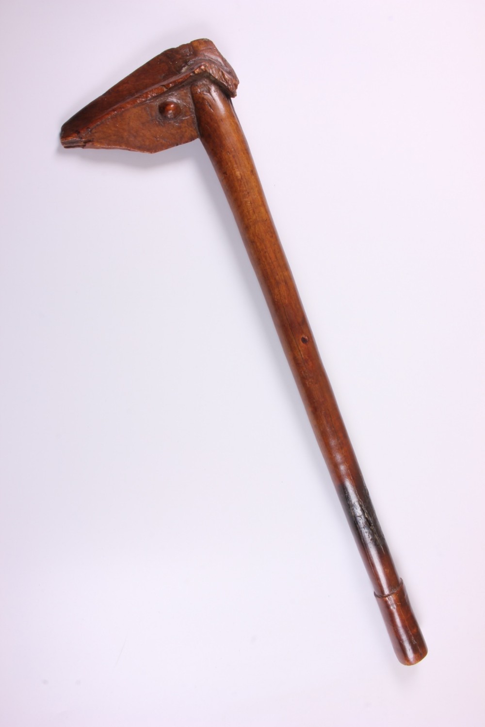 A carved wooden Kanak bird head war club with a smooth tapered shaft and a beak-shaped terminal, crafted from dark brown hardwood.