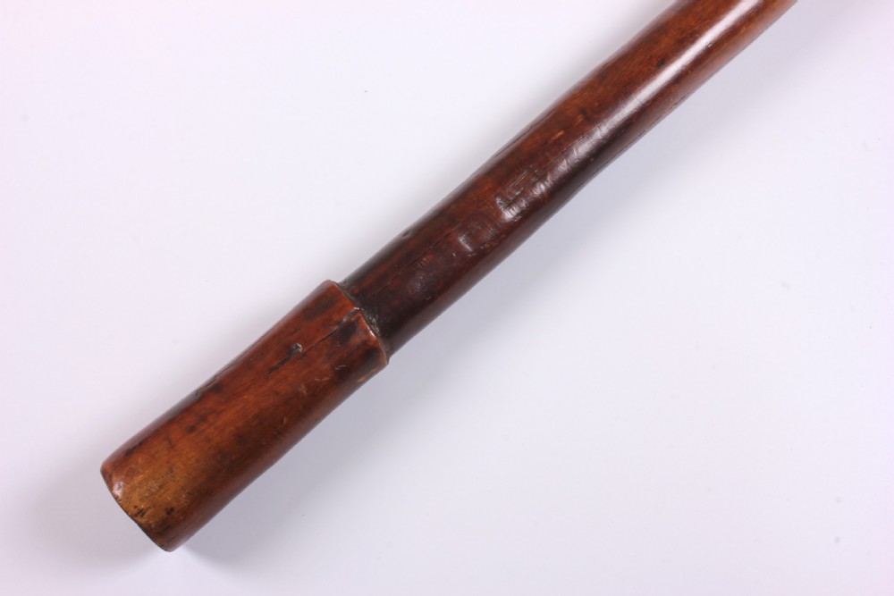 A carved wooden Kanak bird head war club with a smooth tapered shaft and a beak-shaped terminal, crafted from dark brown hardwood. View XVI