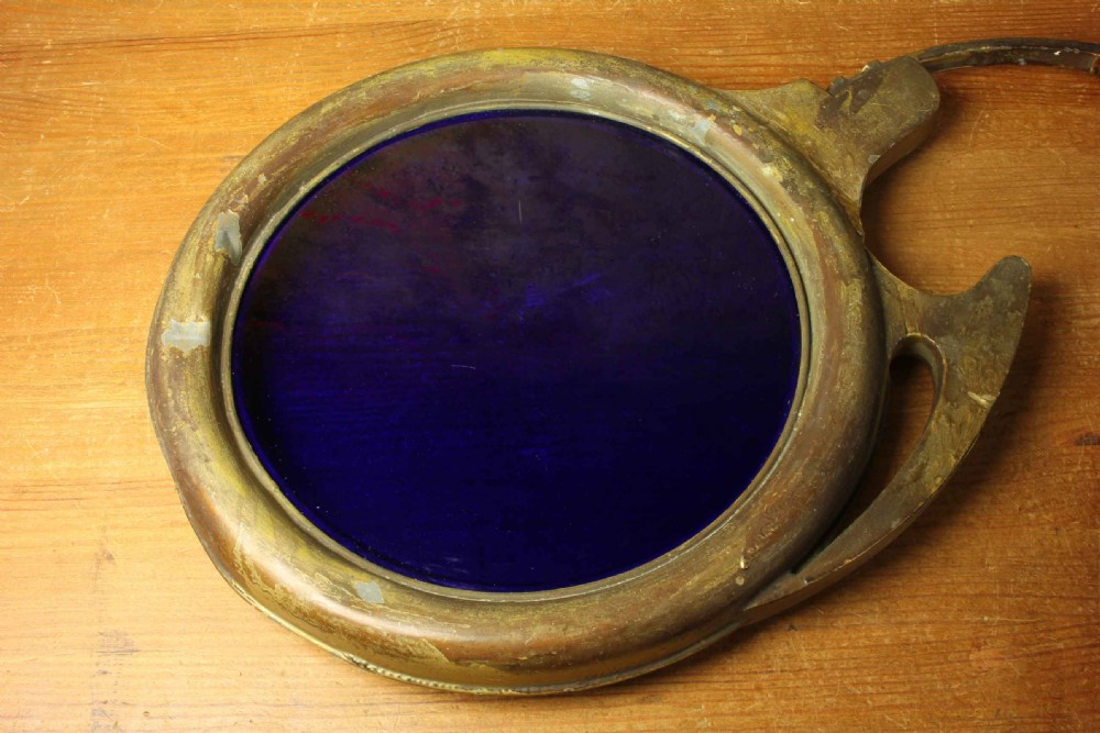 An antique brass optician trade sign in the form of oversized pince-nez spectacles, featuring one red glass lens and one dark blue glass lens. View VII