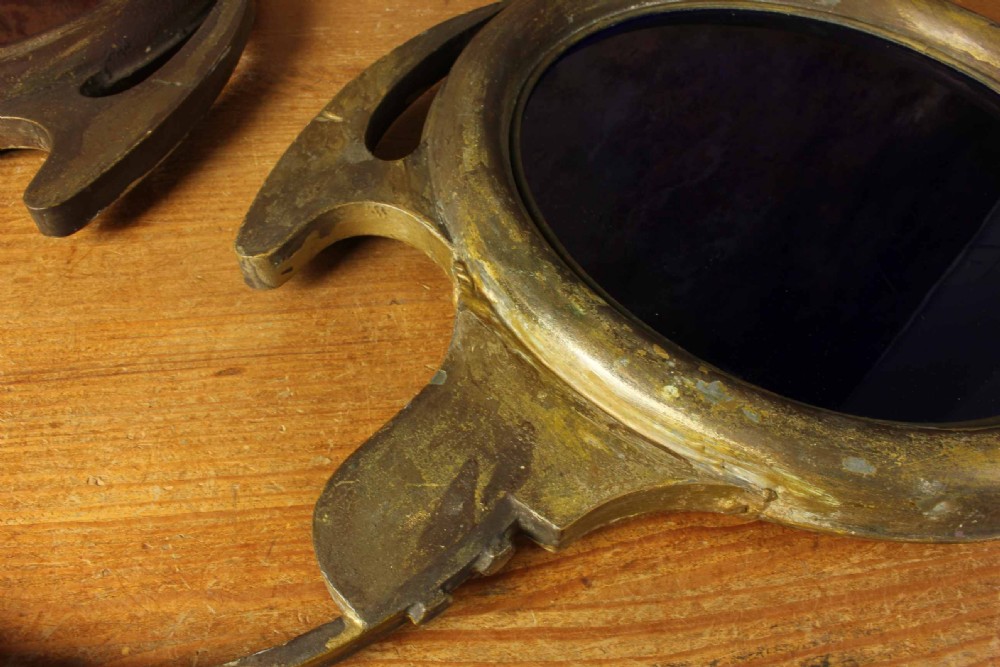 An antique brass optician trade sign in the form of oversized pince-nez spectacles, featuring one red glass lens and one dark blue glass lens. View XV