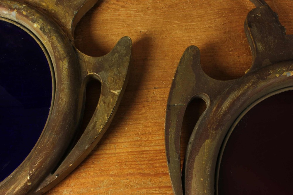 An antique brass optician trade sign in the form of oversized pince-nez spectacles, featuring one red glass lens and one dark blue glass lens. View XXIII