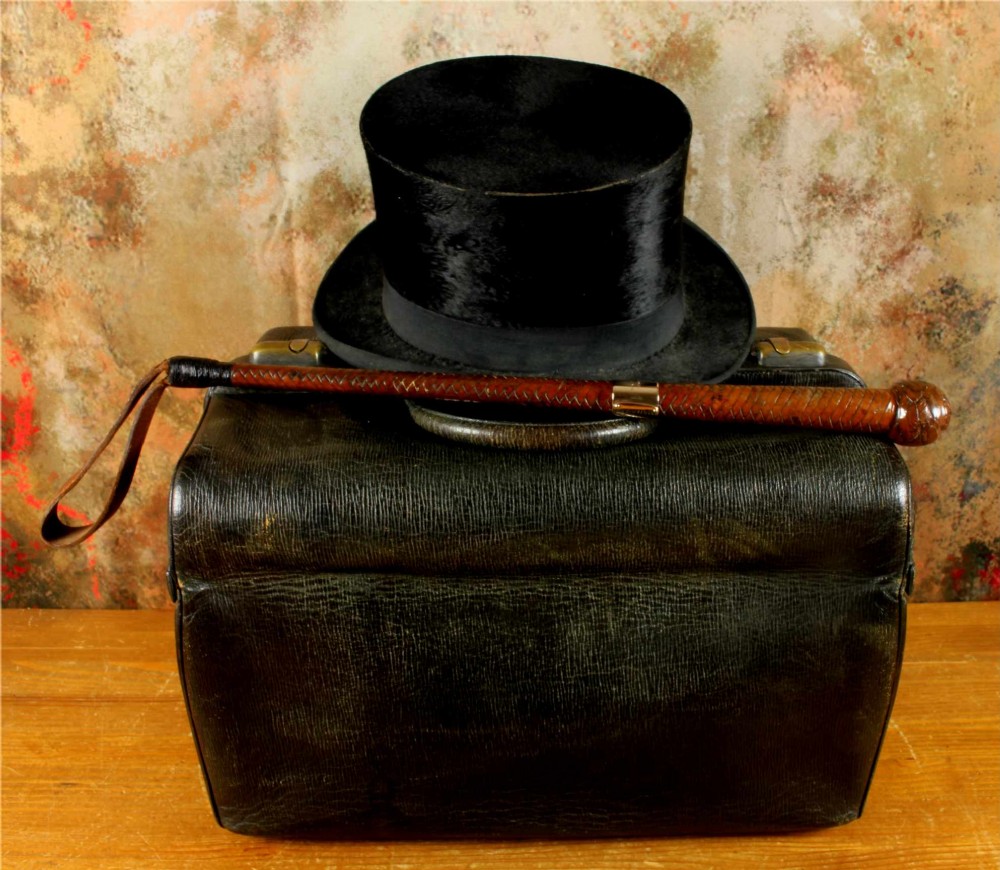 An antique woven dark brown leather riding crop featuring a polished gold collar band and a leather keeper loop at the tip. View IX