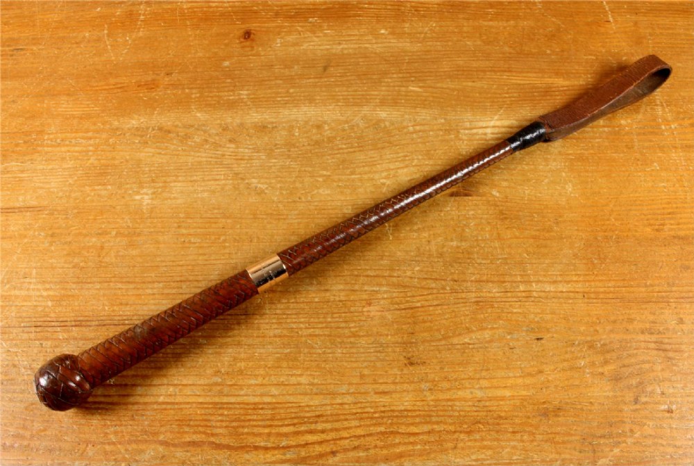 An antique woven dark brown leather riding crop featuring a polished gold collar band and a leather keeper loop at the tip. View XI