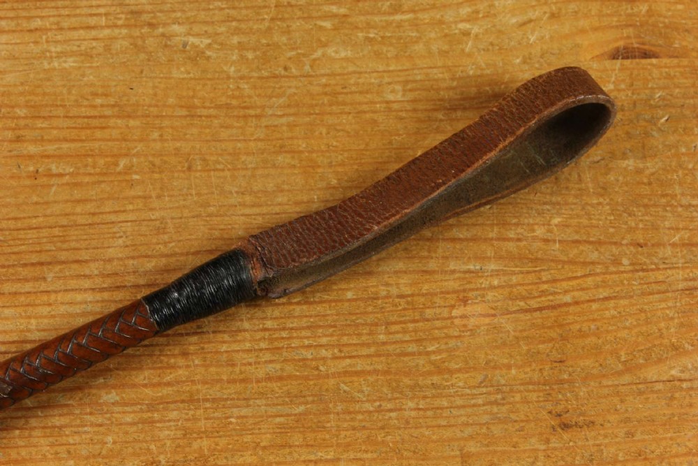 An antique woven dark brown leather riding crop featuring a polished gold collar band and a leather keeper loop at the tip. View XIV