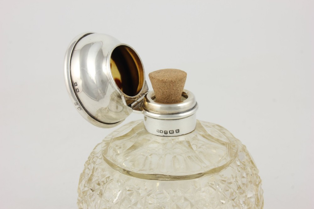 A spherical cut glass scent bottle featuring a hallmarked sterling silver hinged cap inlaid with a round piece of tortoiseshell. View XVI
