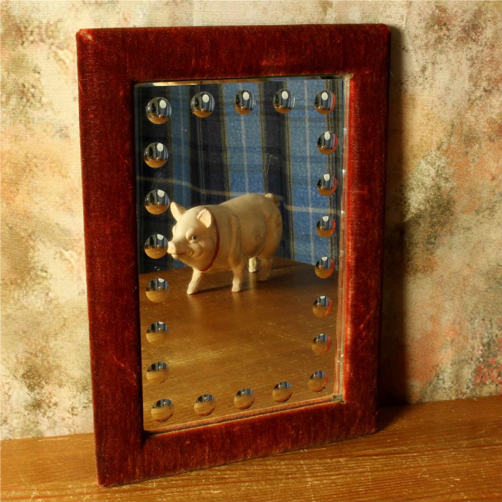 A rectangular Victorian wall mirror featuring a red velvet frame and a perimeter of circular convex lenses cut into the glass.