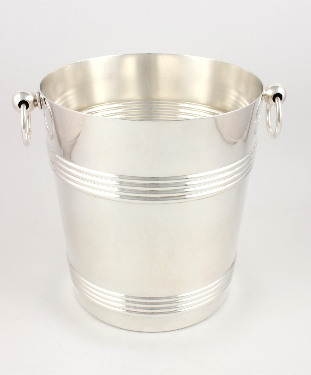 A silver-plated cylindrical champagne cooler featuring horizontal ribbed banding and two side ring handles attached via spherical mounts.