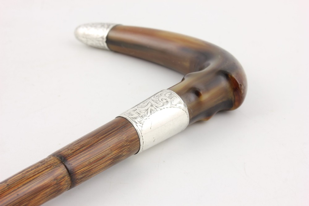 An Edwardian walking stick featuring a curved brown horn handle with a silver tip and an engraved sterling silver collar attached to a dark bamboo shaft. View IV
