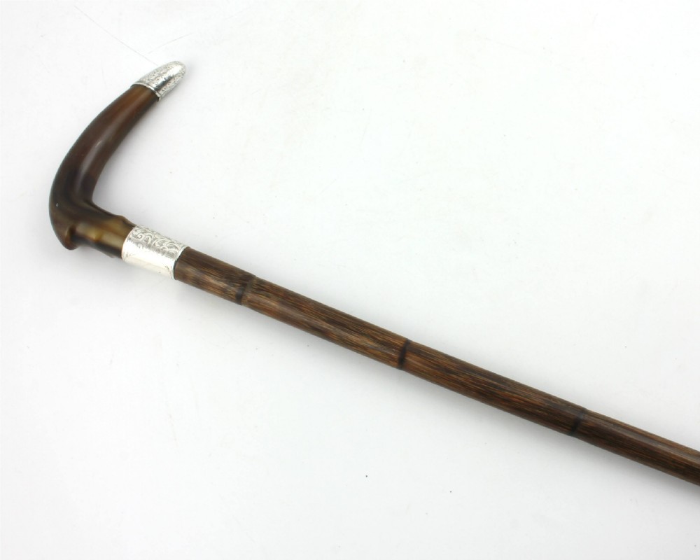 An Edwardian walking stick featuring a curved brown horn handle with a silver tip and an engraved sterling silver collar attached to a dark bamboo shaft. View VIII