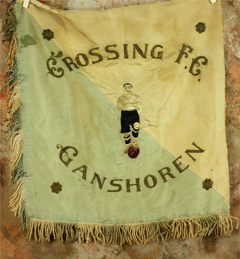 A square two-tone silk banner featuring pale green and cream diagonal panels, embroidered lettering reading Crossing FC Ganshoren, a central footballer figure, and fringe trim.