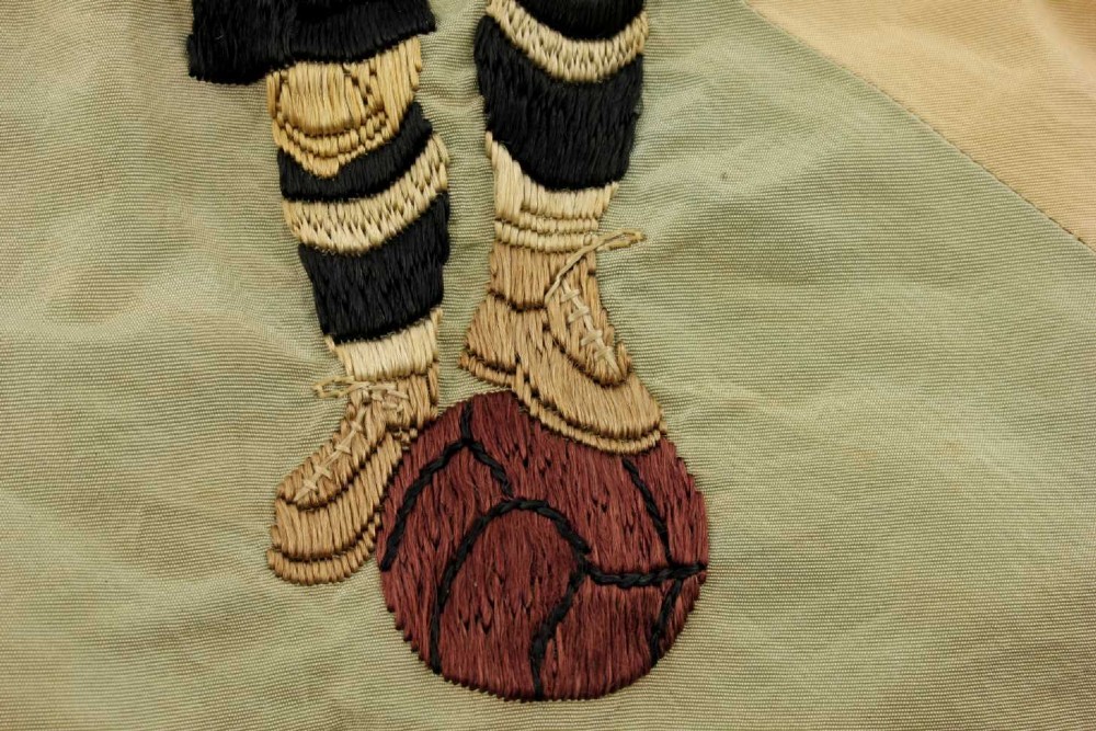 A square two-tone silk banner featuring pale green and cream diagonal panels, embroidered lettering reading Crossing FC Ganshoren, a central footballer figure, and fringe trim. View VIII