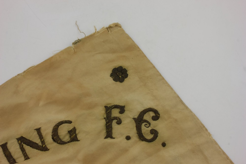 A square two-tone silk banner featuring pale green and cream diagonal panels, embroidered lettering reading Crossing FC Ganshoren, a central footballer figure, and fringe trim. View XIII