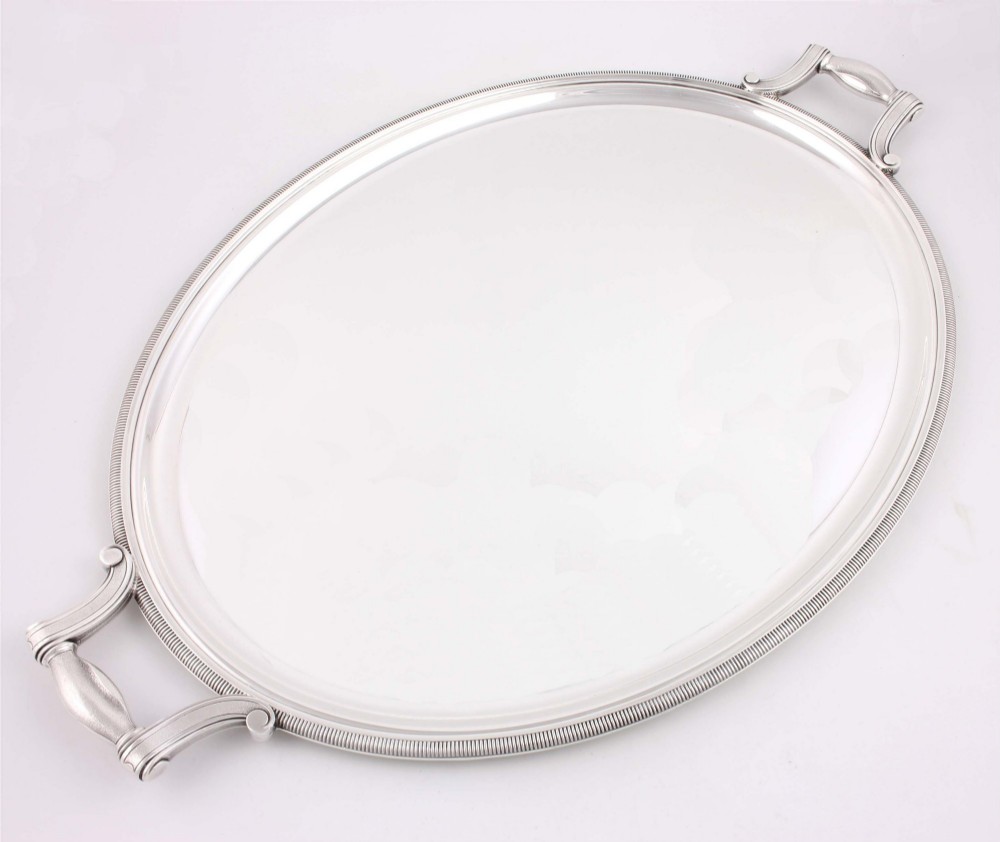 An extra large oval silver-plated tray with reeded border detail and two outer scroll handles on a plain background.