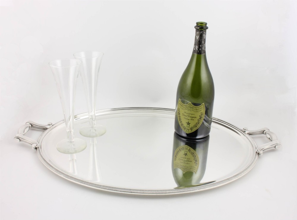 An extra large oval silver-plated tray with reeded border detail and two outer scroll handles on a plain background. View II