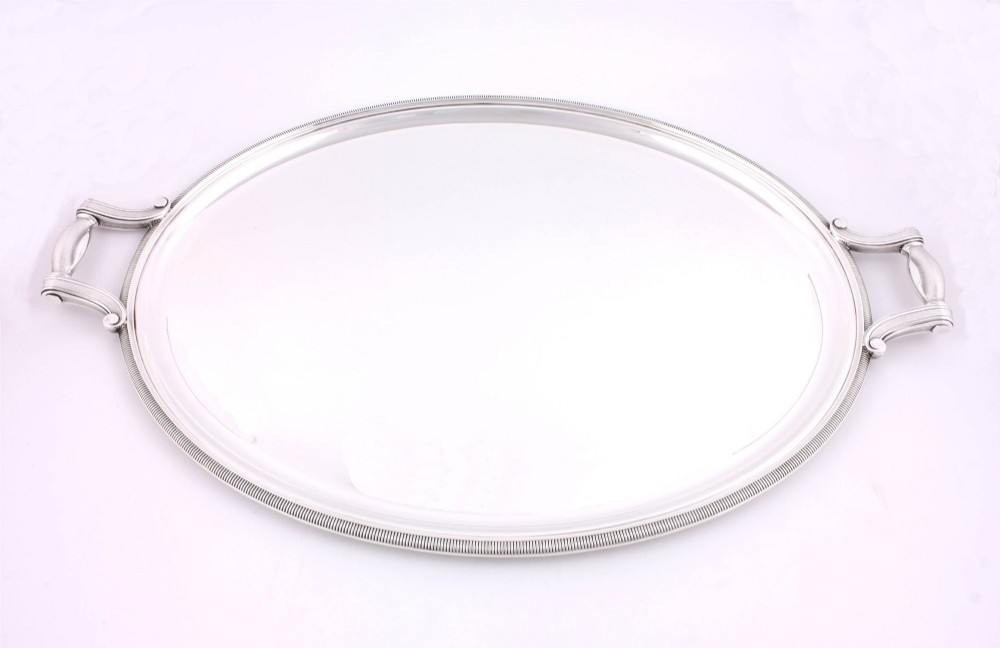 An extra large oval silver-plated tray with reeded border detail and two outer scroll handles on a plain background. View III