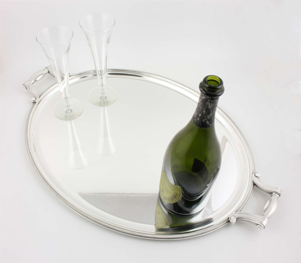 An extra large oval silver-plated tray with reeded border detail and two outer scroll handles on a plain background. View V