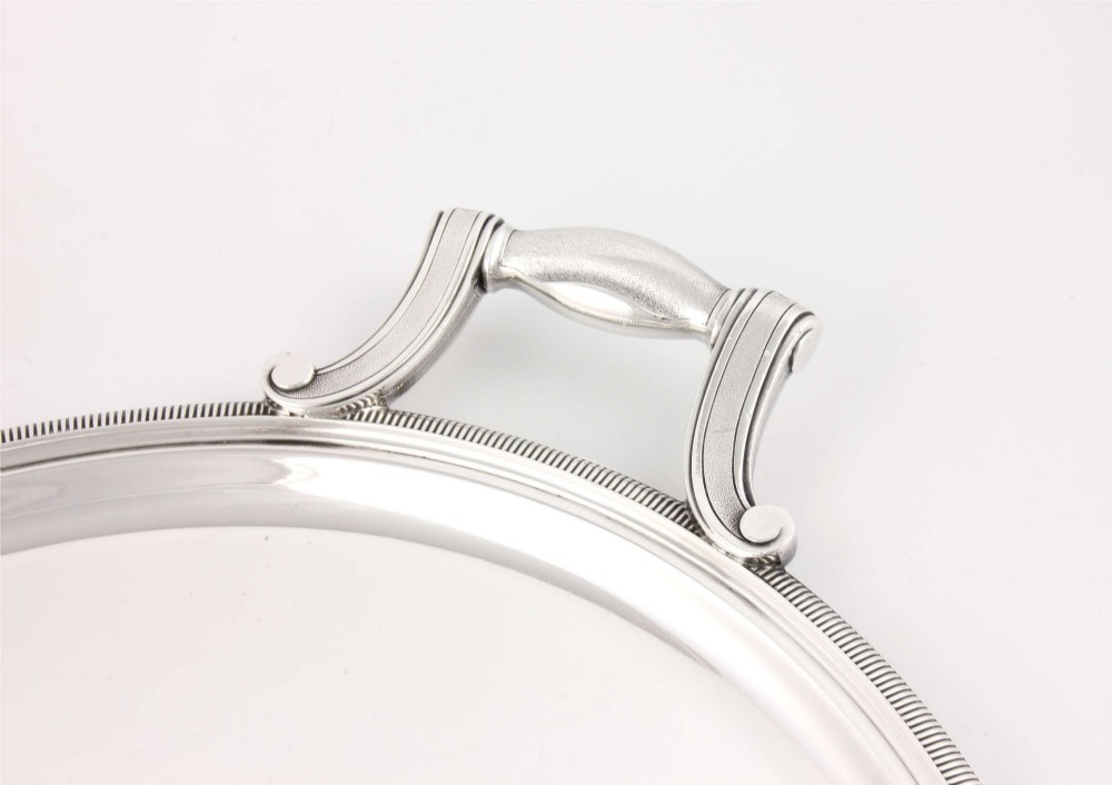 An extra large oval silver-plated tray with reeded border detail and two outer scroll handles on a plain background. View VI