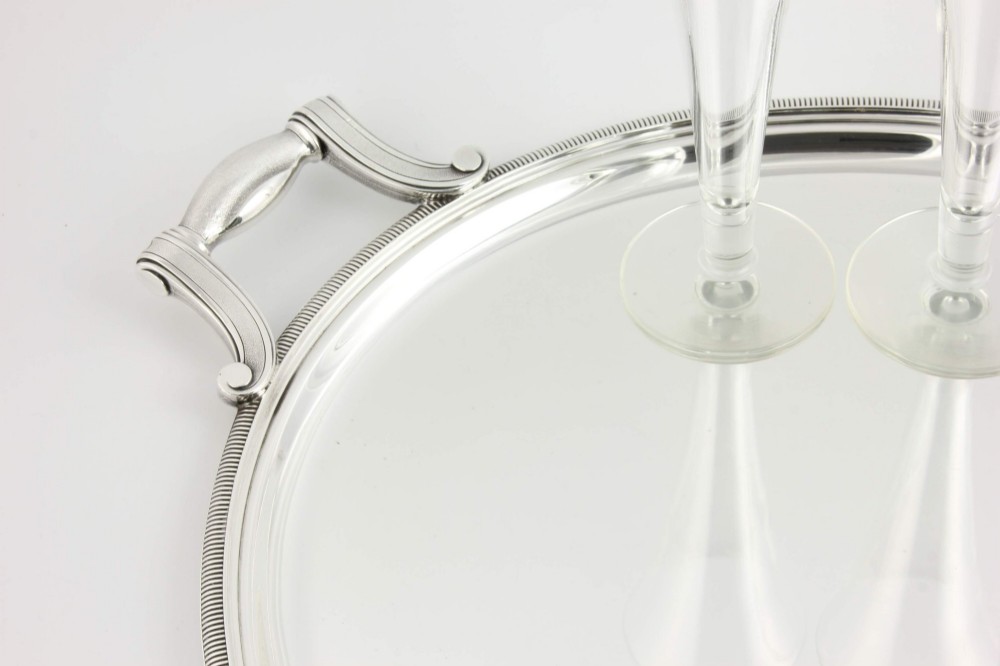 An extra large oval silver-plated tray with reeded border detail and two outer scroll handles on a plain background. View VII
