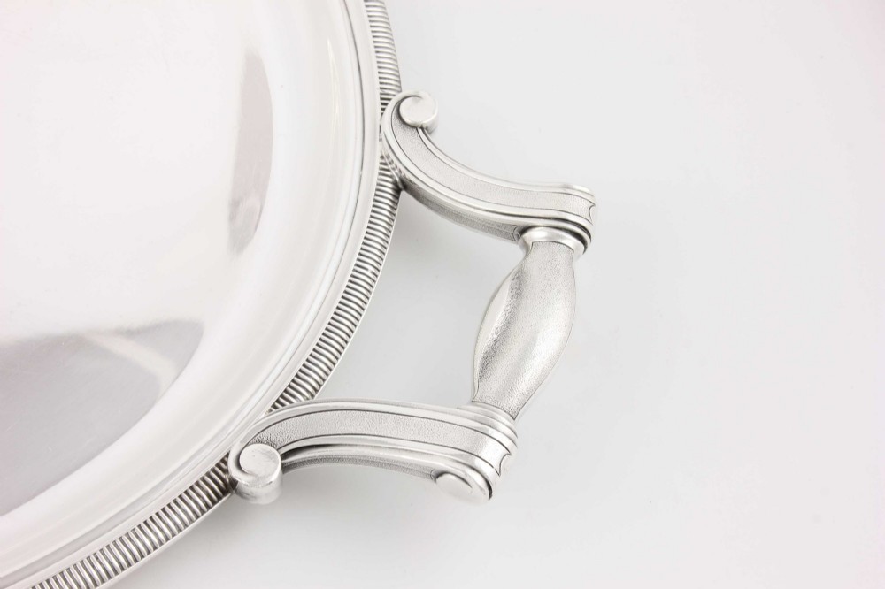 An extra large oval silver-plated tray with reeded border detail and two outer scroll handles on a plain background. View IX