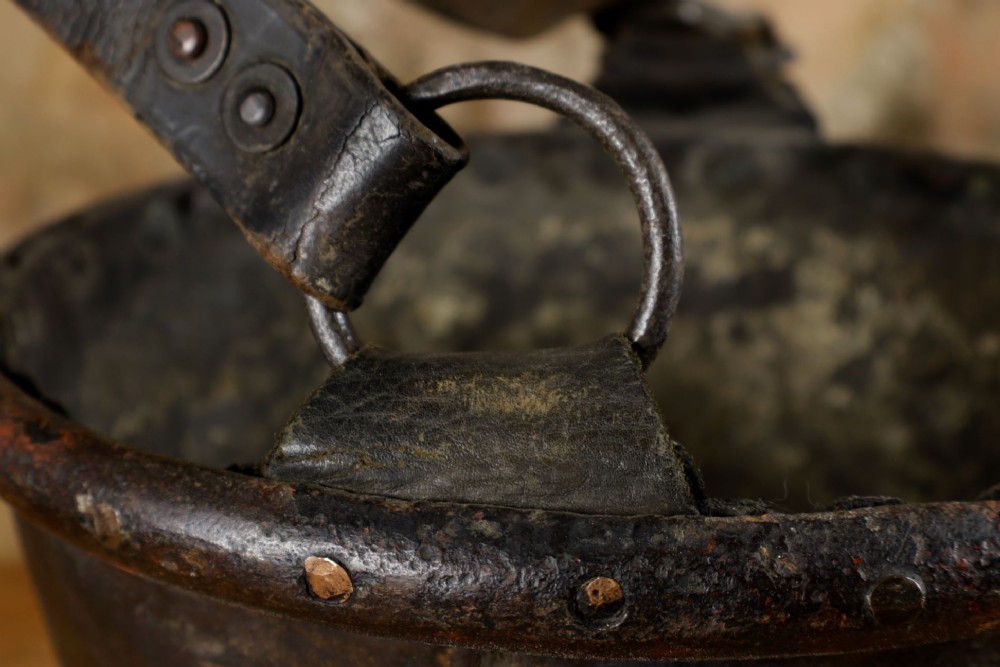 A dark brown Georgian leather fire bucket featuring a heavy strap handle, brass studs around the base, and a painted royal coat of arms with a lion and unicorn. View XIII