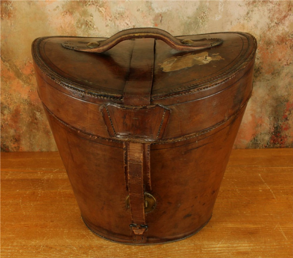An open Victorian brown leather hat case featuring a padded bright red quilted silk lining and removable hat support collars. View X