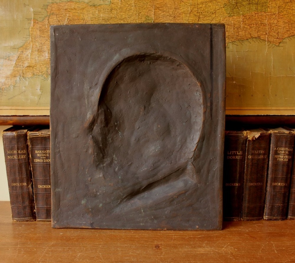 A dark brown bronze rectangular plaque featuring a low-relief profile portrait of a man facing right. View V